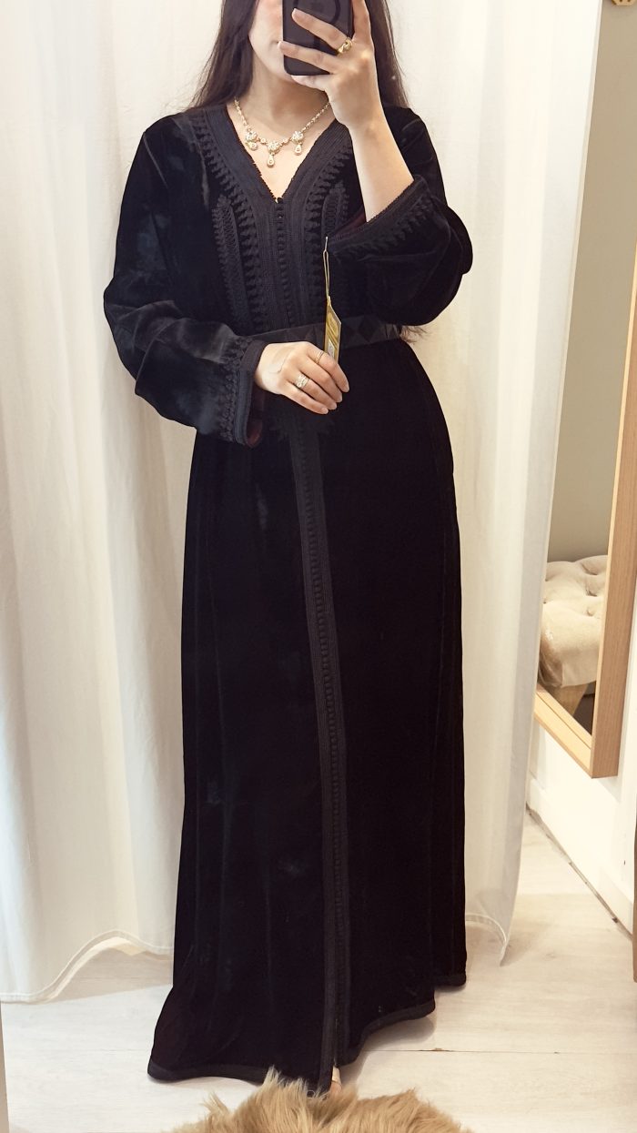 une femme porte un caftan noir en velours avec ceinture