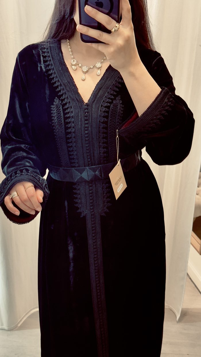 une femme porte un caftan noir en velours avec ceinture