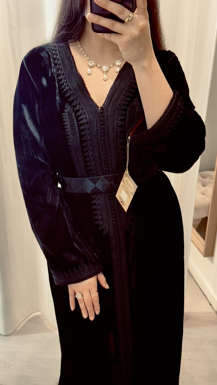 une femme porte un caftan noir en velours avec ceinture