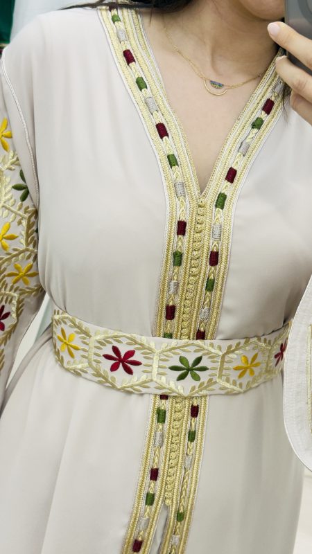 Caftan marocain crème avec broderies multicolores et ceinture assortie porté par une femme – manches larges brodées à la main.